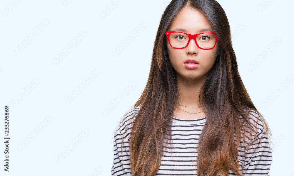 Young asian woman wearing glasses over isolated background with serious expression on face. Simple and natural looking at the camera. Young asian woman wearing glasses over isolated background with serious expression on face. Simple and natural looking at the camera.