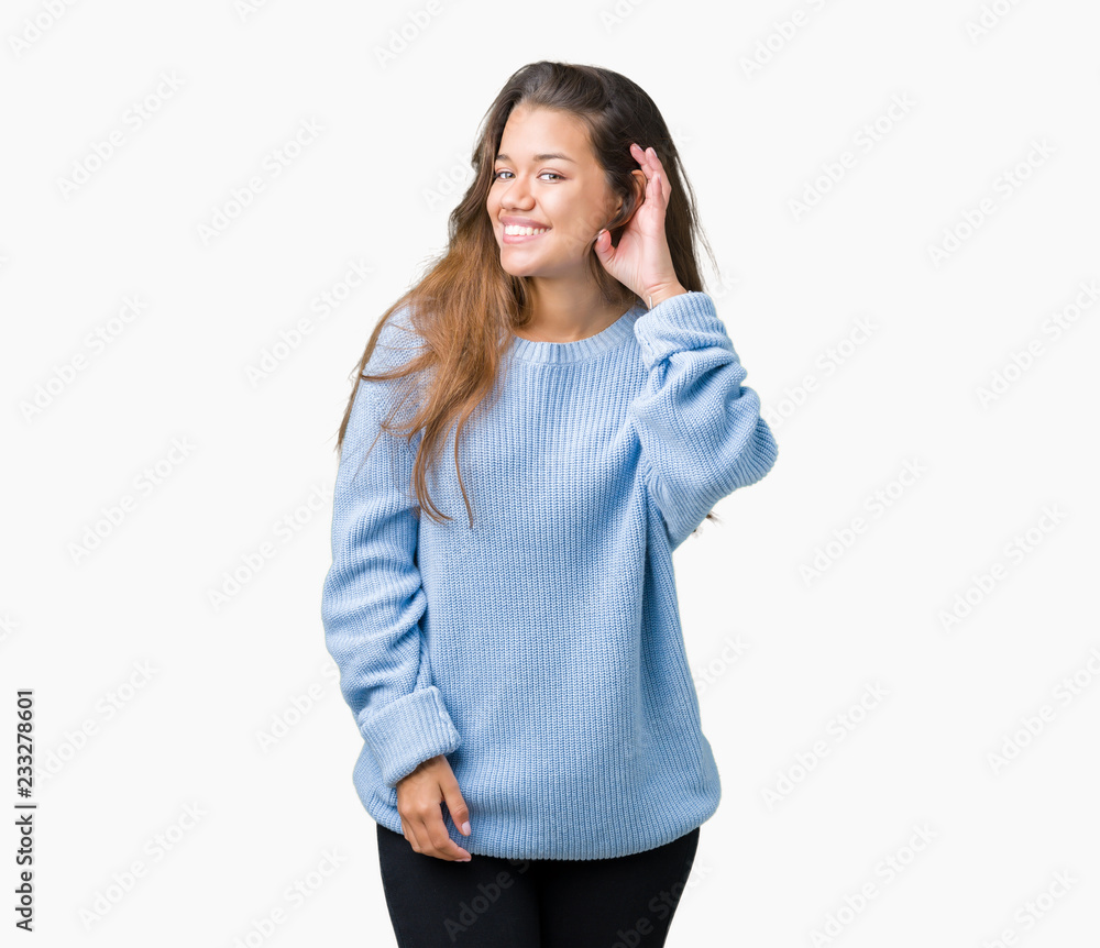Young beautiful brunette woman wearing blue winter sweater over isolated background smiling with hand over ear listening an hearing to rumor or gossip. Deafness concept. Young beautiful brunette woman wearing blue winter sweater over isolated background smiling with hand over ear listening an hearing to rumor or gossip. Deafness concept.