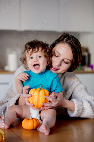 Happy white mother and son with pumpkin. Domestic image at kitchen