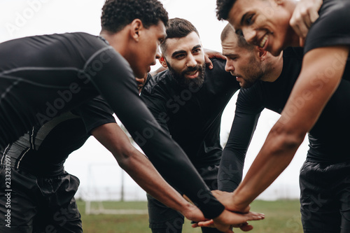 Fototapeta Naklejka Na Ścianę i Meble -  Football players in a huddle holding hands