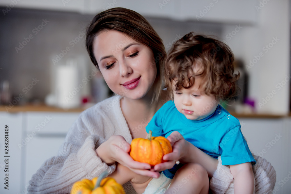Happy white mother and son with pumpkin. Domestic image at kitchen Happy white mother and son with pumpkin. Domestic image at kitchen