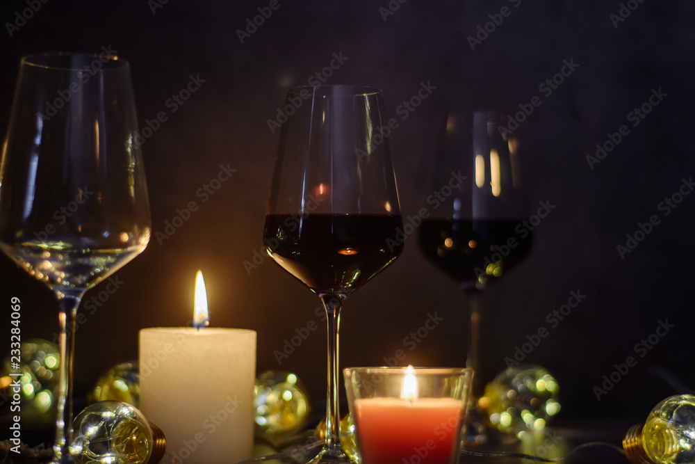 Holidays composition made of glass of red wine, candles and garlands on a dark background Holidays composition made of glass of red wine, candles and garlands on a dark background