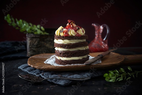 Cream cake with strawberry sauce served on wooden board photo