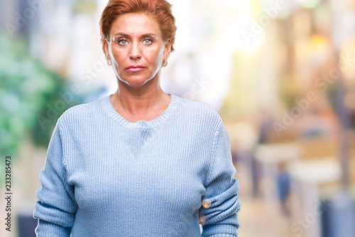 Atrractive senior caucasian redhead woman over isolated background with serious expression on face. Simple and natural looking at the camera.