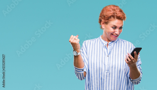 Canvas Print Atrractive senior caucasian redhead woman texting using smartphone over isolated
