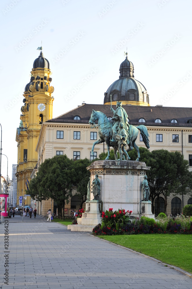 Fototapeta premium Statue eines Königs auf Pferd, Reiter in München mit Krone mit Blick auf Theatiner Kirche