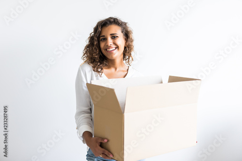 Young latin american woman moving into new apartment holding cardboard boxes with belongings