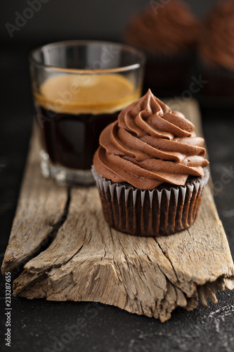 Dark chocolate cupcake with ganache frosting, espresso in glass photo