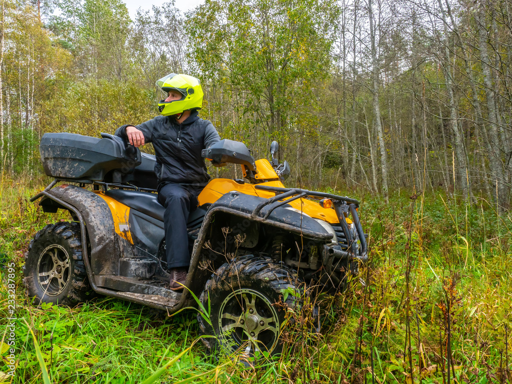A man travels on ATV. Yellow quad bike. Off-road travel. The man in the helmet. Yellow ATV. A man travels on ATV. Yellow quad bike. Off-road travel. The man in the helmet. Yellow ATV.