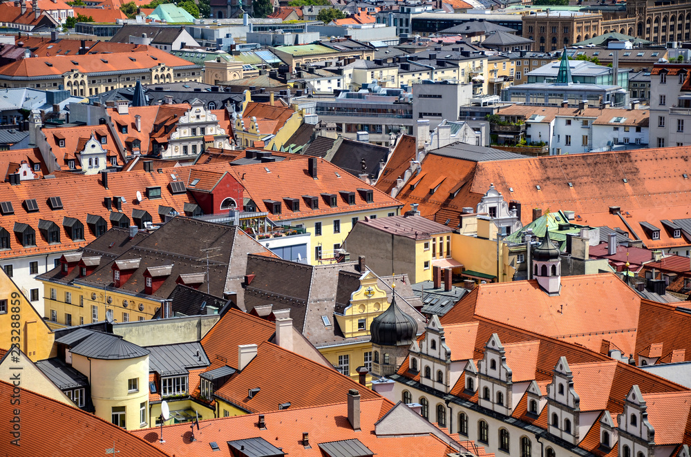 Dense urban cityscape of red rooftops and colorful buildings in yellow, white, and green colors in the city center of Munich, Germany