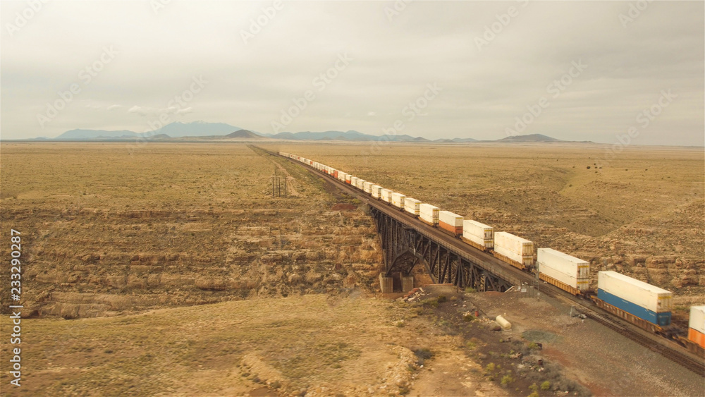 AERIAL: Train crossing steel arch railroad bridge across the Canyon Diablo