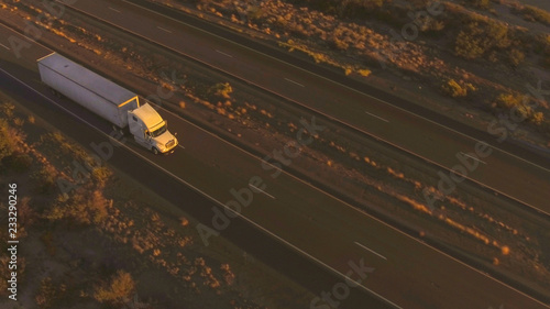 Fotografie AERIAL: Flying above freight semi truck transporting goods on busy highway