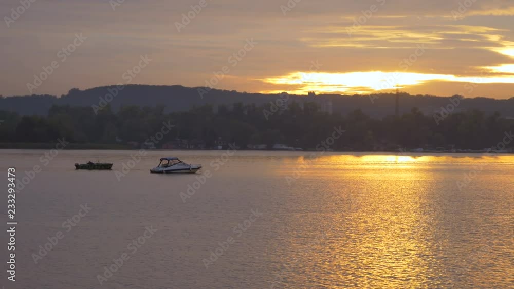 Expensive boat and cheap boat on the water at a beautiful sunset. Rest outside the city. Evening horizon. Different status Expensive boat and cheap boat on the water at a beautiful sunset. Rest outside the city. Evening horizon. Different status