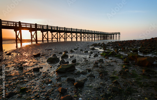 Overview of beautiful fishing pier at sunrise at low tide at Walnut Beach, Milford Connecticut, USA. Walnut Beach is a great place to spend the day strolling along the edge of the Long Island Sound.
