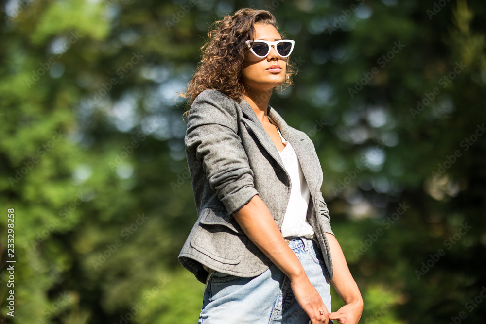 Close-up lifestyle fashion portrait of young american woman walking at park , travel with backpack Close-up lifestyle fashion portrait of young american woman walking at park , travel with backpack