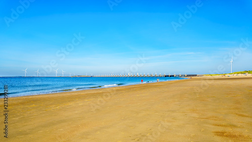 Fototapeta Naklejka Na Ścianę i Meble -  The wide and clean sandy beach at Banjaardstrand along the Oosterschelde inlet at the Schouwen-Duiveland peninsula in Zeeand Province in the Netherlands. The Storm Surge Barrier in the background