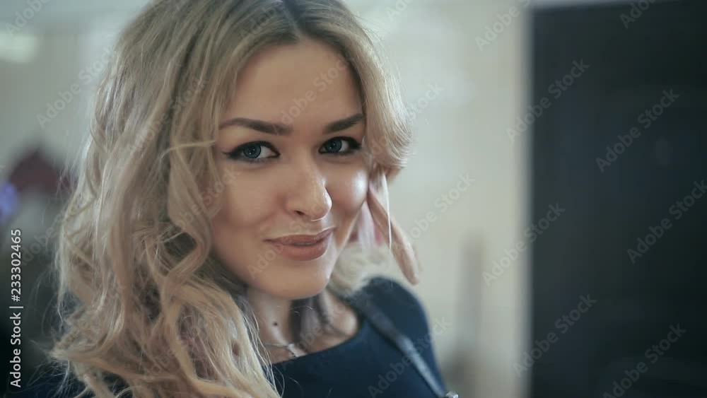 blonde in a short black dress and high boots with bright makeup repairing the car in the garage blonde in a short black dress and high boots with bright makeup repairing the car in the garage