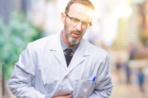 Middle age senior hoary professional man wearing white coat over isolated background with hand on stomach because nausea, painful disease feeling unwell. Ache concept.