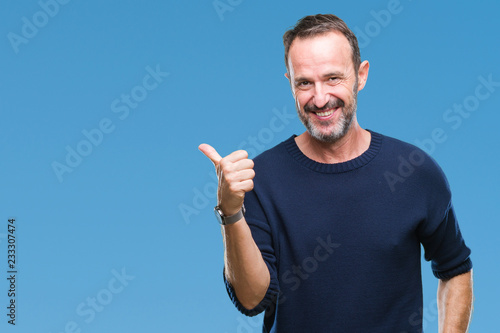 Middle age hoary senior man over isolated background smiling with happy face looking and pointing to the side with thumb up.