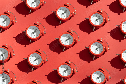 The red clock is lined up in rows on a bright red background. Festive Christmas or New Year concept. Minimalism in the style of pop art. Copy space