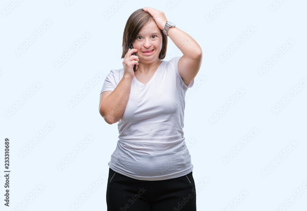 Young adult woman with down syndrome taking using smartphone over isolated background stressed with hand on head, shocked with shame and surprise face, angry and frustrated. Fear Young adult woman with down syndrome taking using smartphone over isolated background stressed with hand on head, shocked with shame and surprise face, angry and frustrated. Fear