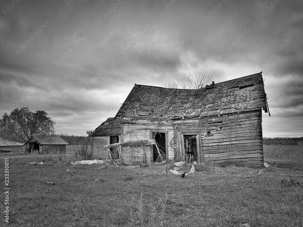 Black and white image of dreary abandoned dilapidated farm house with cloudy skies in northern Minnesota Black and white image of dreary abandoned dilapidated farm house with cloudy skies in northern Minnesota