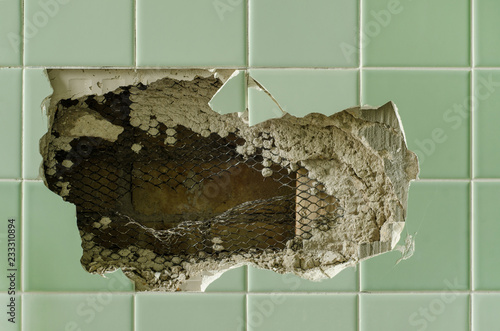 Hole in broken bathroom wall tile