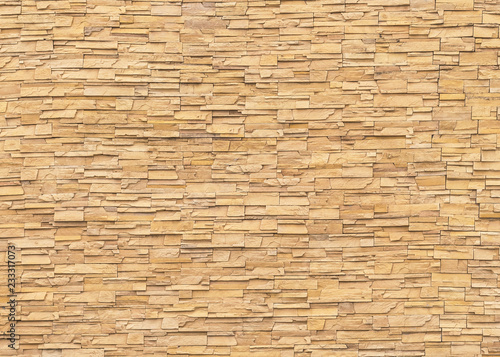 Rock stone brick tile wall aged texture detailed pattern background in light yellow cream brown color