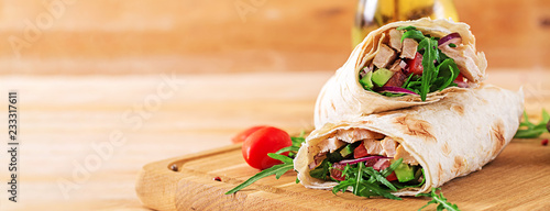 Tortillas wraps with chicken and vegetables on  wooden background. Chicken burrito. Banner. Healthy food.