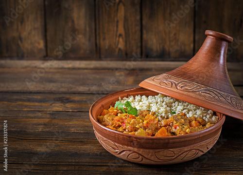 Traditional tajine dishes, couscous  and fresh salad  on rustic wooden table. Tagine lamb meat and pumpkin.