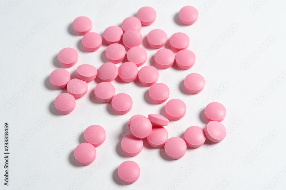 pink pills scattered on a white background.