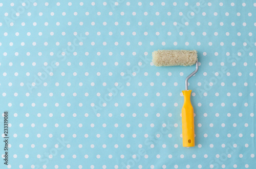 yellow paint roller over blue polka dot wallpaper