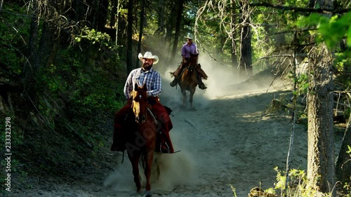 Horses galloping in Roundup on Dude Ranch with cowboy and cowgirl riders  photo