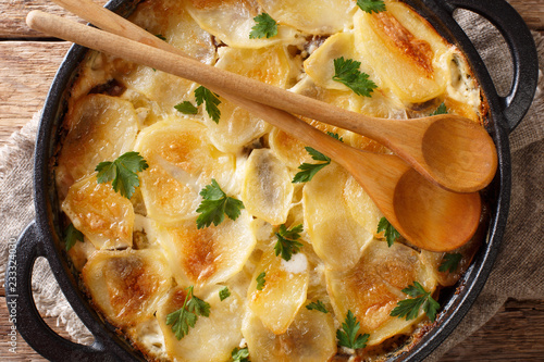 Janssonin Kiusaus baked potato with anchovy fillets, onions and heavy cream close-up in a frying pan. horizontal top viewl. Finnish food photo