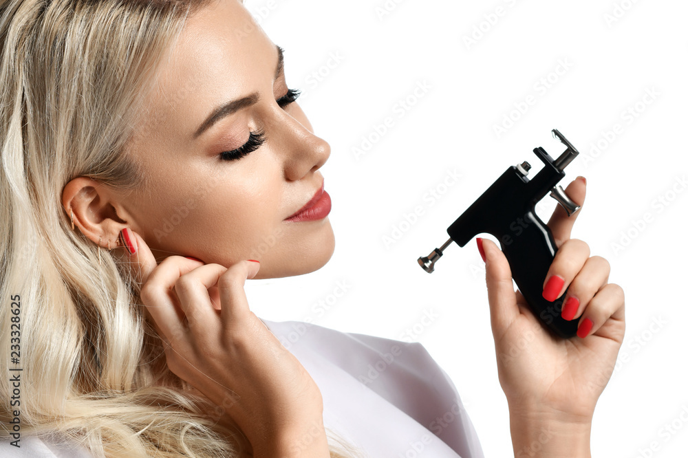 Woman beautician cosmetologist hold Ear Piercing Gun looking at the corner isolated on white Woman beautician cosmetologist hold Ear Piercing Gun looking at the corner isolated on white