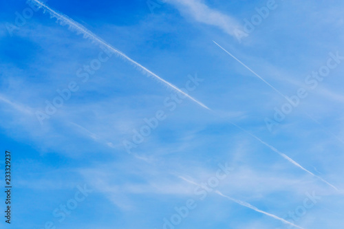 Three jet trails in the clear blue sky with white clouds