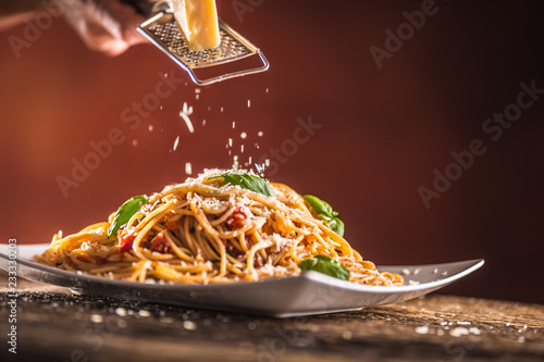 Italian pasta spaghetti with tomato sauce basil and parmesan cheese in white plate