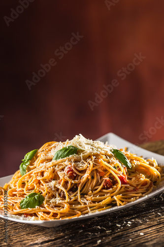 Italian pasta spaghetti with tomato sauce basil and parmesan cheese in white plate