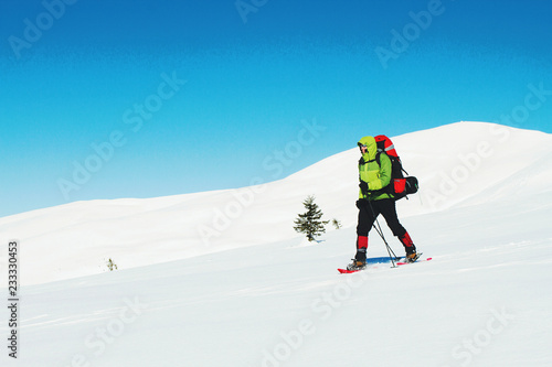 Winter hiking in the mountains with a backpack in snowshoes.