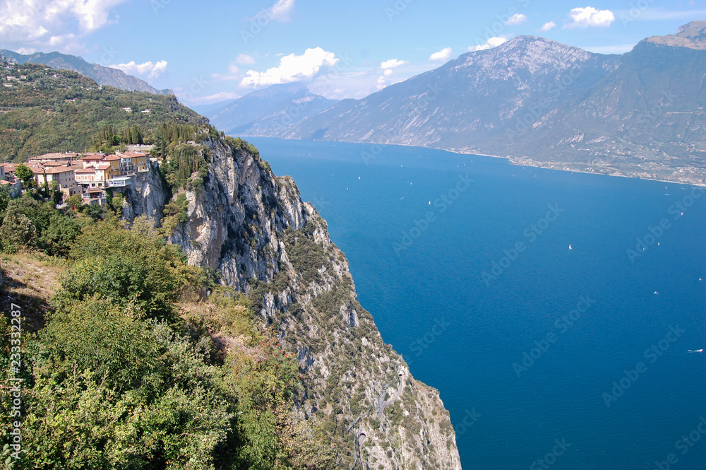 Mountains and a lake,/ Panoramic view from a great height on the lake surrounding Lake Garda. On the cliffs you can see a mountain road and tunnels.