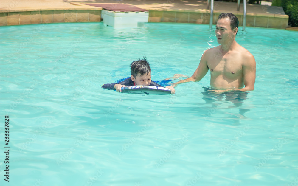 Man and boy play in the water in the swimming pool.