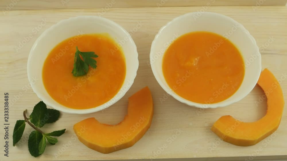Pumpkin soup with parsley in white bowls on wooden board Pumpkin soup with parsley in white bowls on wooden board