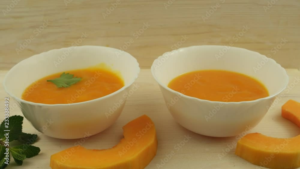Pumpkin soup with parsley in white bowls on wooden board Pumpkin soup with parsley in white bowls on wooden board