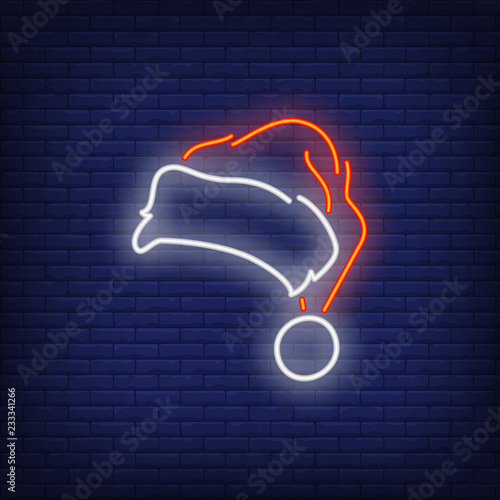 Red and white santa hat neon sign. Glowing hat on dark blue brick background. Can be used for winter, christmas time, festive