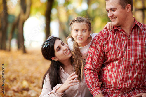 Happy family is in autumn city park. Children and parents. They posing, smiling, playing and having fun. Bright yellow trees.