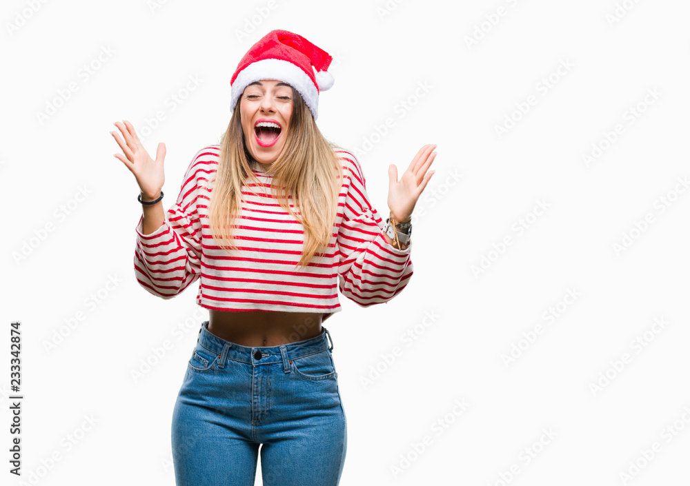 Young beautiful woman wearing christmas hat over isolated background celebrating mad and crazy for success with arms raised and closed eyes screaming excited. Winner concept Young beautiful woman wearing christmas hat over isolated background celebrating mad and crazy for success with arms raised and closed eyes screaming excited. Winner concept