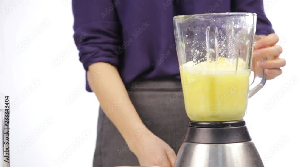 Woman making a fruit cocktail in a blender, smoothies preparation. Woman making a fruit cocktail in a blender, smoothies preparation.