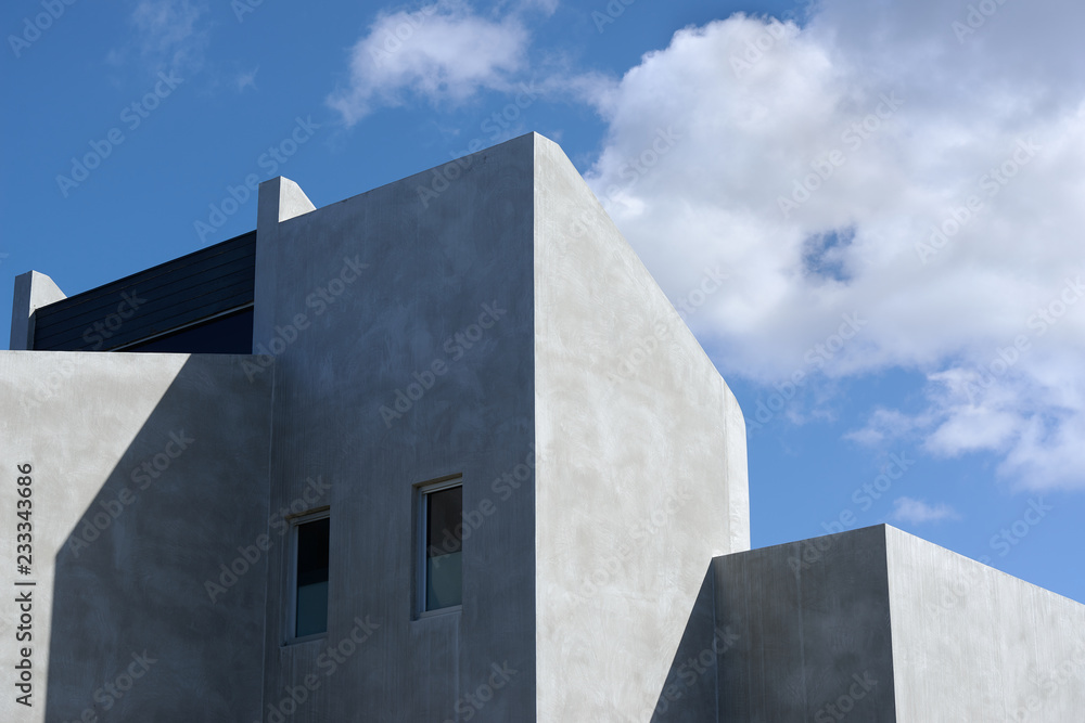 Architectural detail of a modern concrete residential building against a cloudy blue sky. Architectural detail of a modern concrete residential building against a cloudy blue sky.