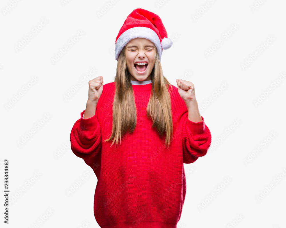 Young beautiful girl wearing christmas hat over isolated background excited for success with arms raised celebrating victory smiling. Winner concept. Young beautiful girl wearing christmas hat over isolated background excited for success with arms raised celebrating victory smiling. Winner concept.