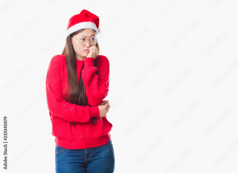 Young Chinese woman over isolated background wearing christmas hat looking stressed and nervous with hands on mouth biting nails. Anxiety problem. Young Chinese woman over isolated background wearing christmas hat looking stressed and nervous with hands on mouth biting nails. Anxiety problem.